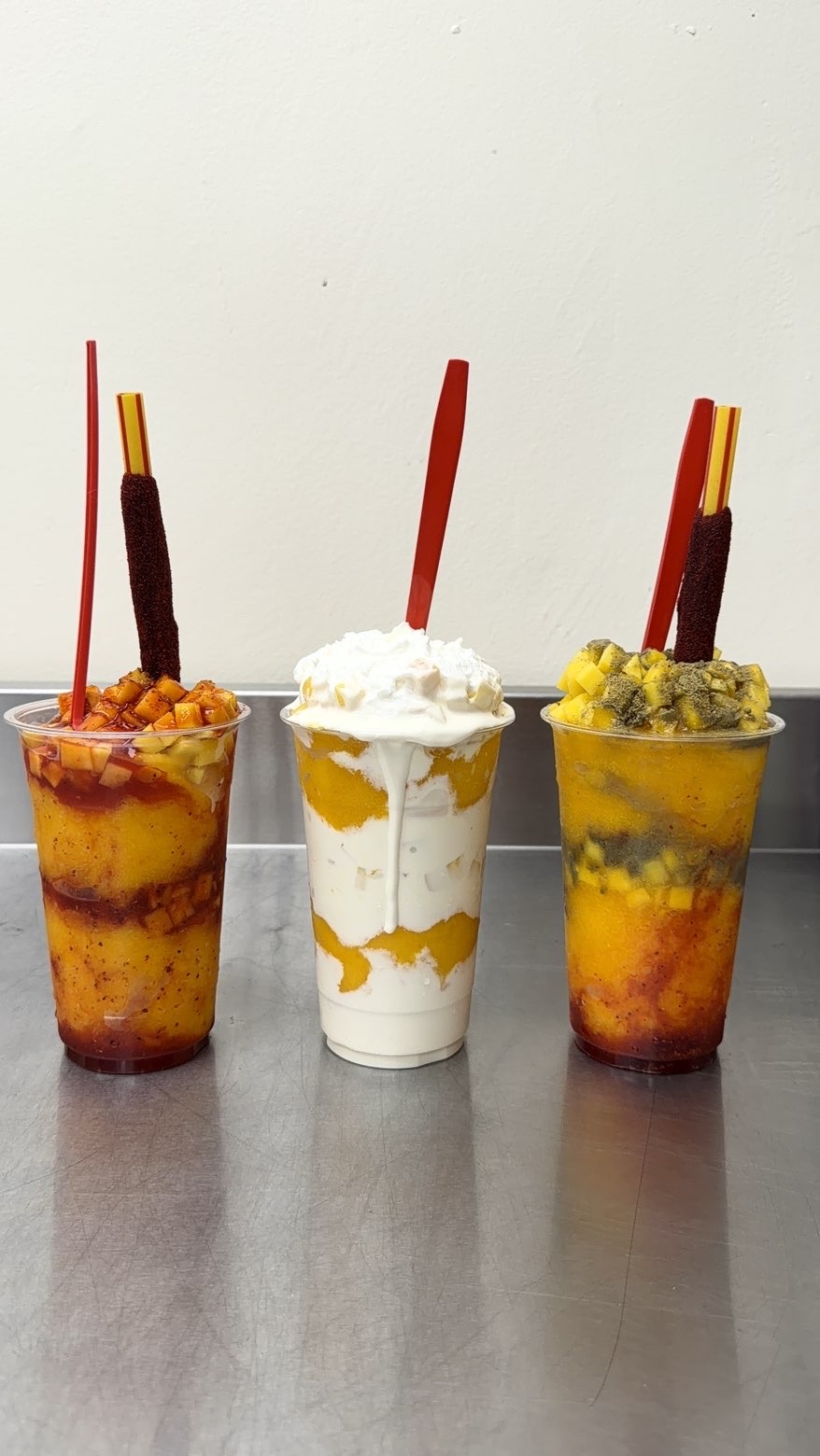 Three Lopez Market mangonadas on a stainless-steel counter